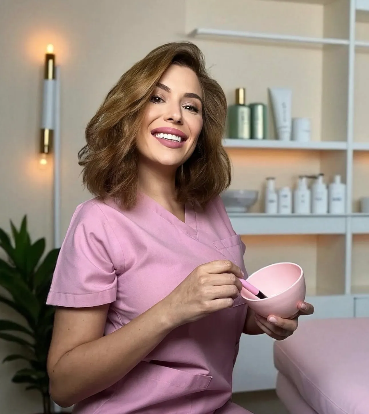 Andreea in the treatment room, smiling, holding a bowl and brush