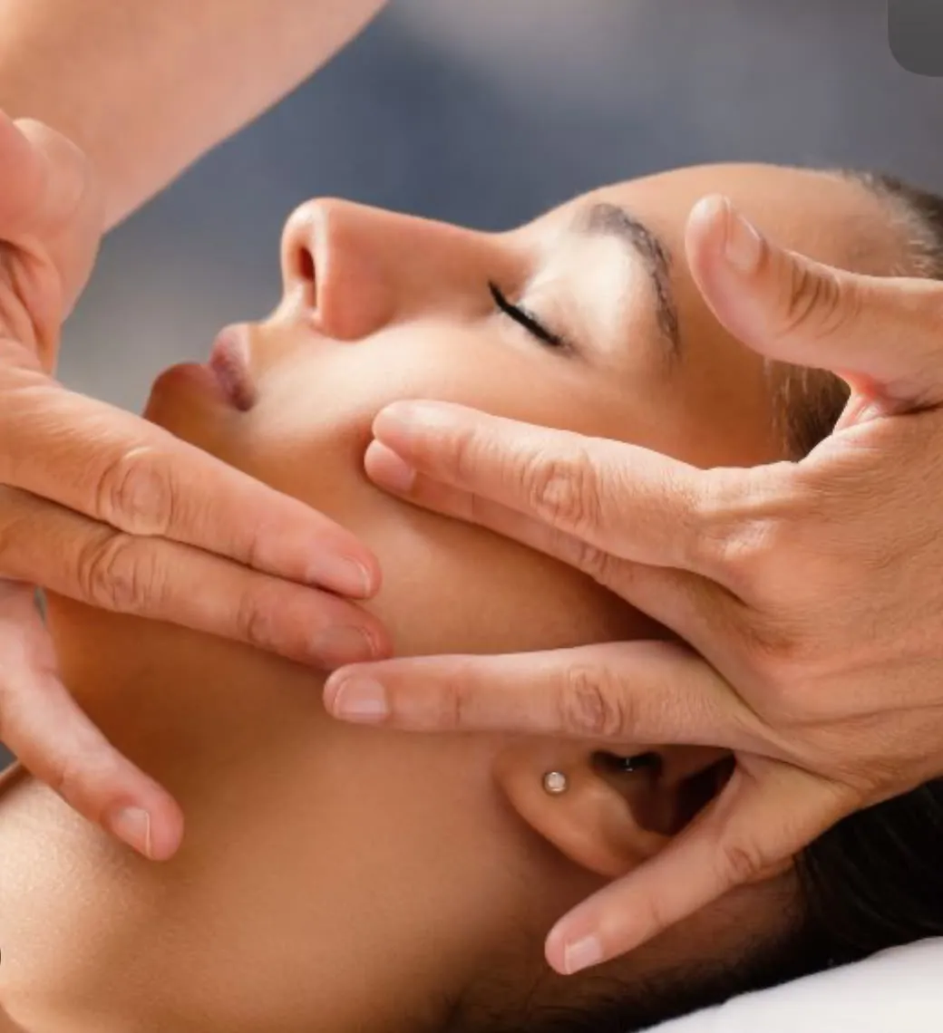 Two hands working along a client’s cheek and jaw during a facial sculpting massage